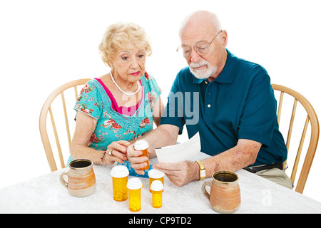 Senior couple reading instructions from the pharmacy on how to take their medication. White background.  Stock Photo