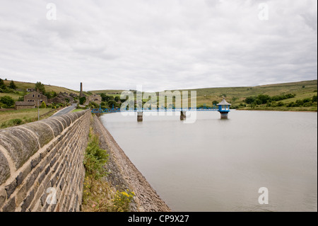 Calm water of Leeming Reservoir, embankment, footbridge & valve tower, set in moorland of Pennine uplands - Nr Oxenhope, West Yorkshire, England, UK.