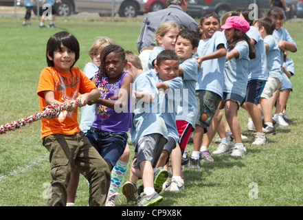 children pulling rope during tug of war game at school field day fun ...