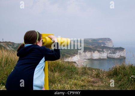 A young girl looking through a coin-operated telescope at Flamborough Head. Stock Photo