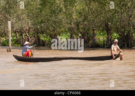 Vietnamese man and woman rowing a long boat, Cai Be, Mekong River Delta, Vietnam Stock Photo