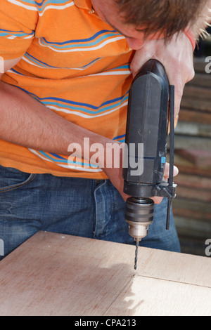Man drilling into wood with an electric power drill powertool Stock Photo