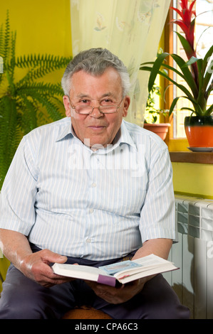 Senior man in 80s reading book at home Stock Photo
