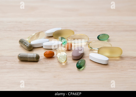 Selection of vitamin supplements (omega 3, Co-enzyme Q10, peppermint, chondroitin, ginkgo and ginseng) on chopping board Stock Photo