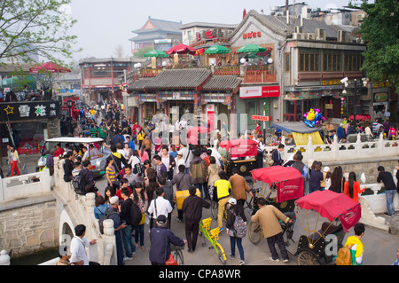 Busy street on historic bridge beside popular tourist location at Houhai Lake in Beijing China Stock Photo