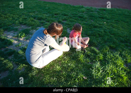 Mother having a serious talk with her six year old daughter outdoors on grass. Stock Photo