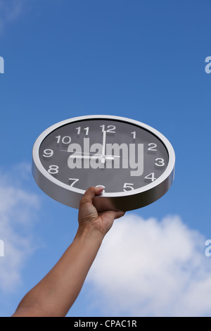 hand holding a wall clock up to the sky Stock Photo