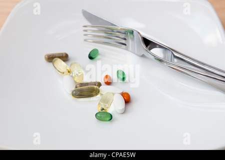 Dinner of a selection of vitamins (omega 3, Co-enzyme Q10, peppermint, chondroitin, ginkgo and ginseng) on white background Stock Photo
