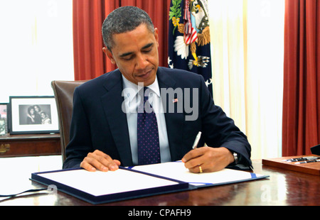 President Barack Obama signs the payroll tax bill (HR3765) in the Oval Office on December 23, 2011. Stock Photo