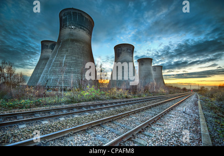 The disused cooling towers at Thorpe Marsh in Yorkshire, England stand by railway tracks against a colorful evening sky Stock Photo