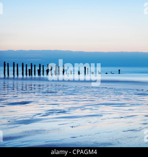 Old sea defences at dawn, smooth water from long exposure. Stock Photo