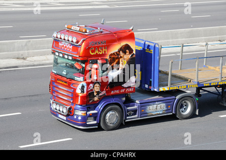Johnny Cash lorry truck art graphics side front view of Scania semi cab tractor unit & flat bed trailer driving along UK motorway highway road England Stock Photo
