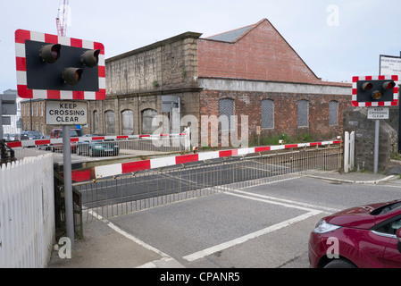 British railway level crossing barrier gate closed before a train passes through in Camborne, UK. Stock Photo
