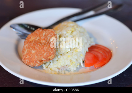 fried rice served with tomato and fried fish cake Stock Photo