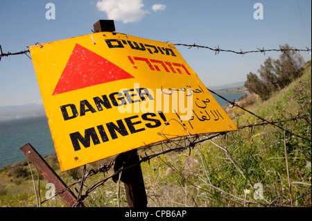 A sign reading 'Danger Mines!' hangs from a barbed wire fence in the Israeli occupied Golan Heights. Stock Photo