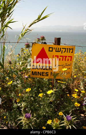 A sign reading 'Danger Mines!' hangs from a barbed wire fence in the Israeli occupied Golan Heights. Stock Photo