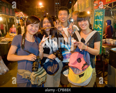 A group of young Chinese people pose for the camera at the well known Zhengning Road night food street market in Lanzhou. Stock Photo