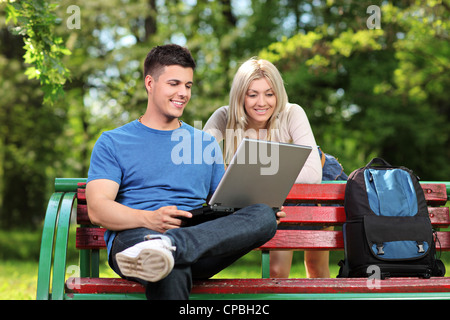 A loving couple working on a laptop in a city park