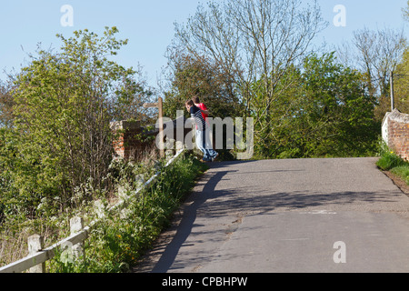 A 'courting couple' standing on a river bridge looking out across the 'Bure Valley' Norfolk, UK Stock Photo