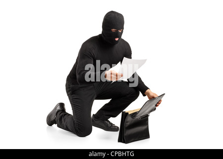 A thief reading a confidential documents after stealing a briefcase isolated on white background Stock Photo