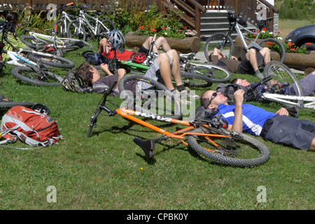 Tired cyclists relaxing on the grass on the mountain bike Tour de Mont Blanc Stock Photo