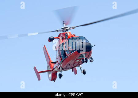 A United States Coast Guard HH-65C Dolphin helicopter approaching a Coast Guard Auxiliary vessel. Stock Photo