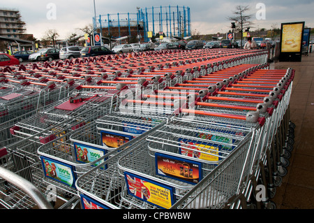 Empty trolleys lined up outside supermarket with gasometer in background Stock Photo