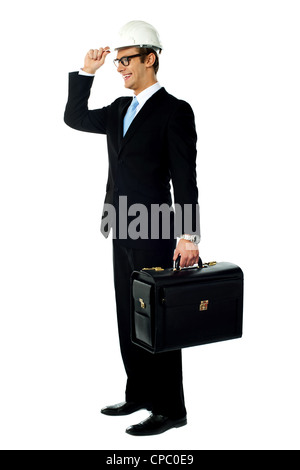 Smiling architect holding his hard hat and briefcase. Looking away Stock Photo