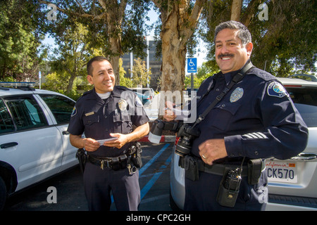 Two Hispanic Santa Ana, CA, police officers meet during a crime scene investigation. Stock Photo