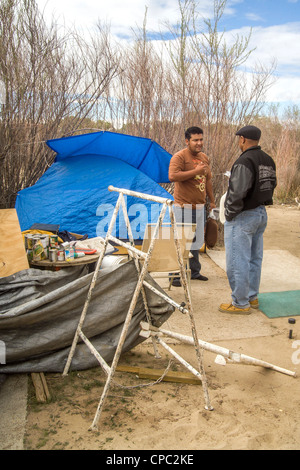 An African American charitable church representative talks with a homeless man living in an outdoor encampment in a desert town Stock Photo