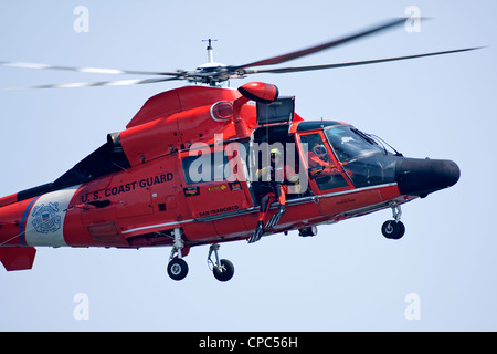 A swimmer prepares to be lowered to the water from a United States Coast Guard HH-65C Dolphin helicopter. Stock Photo