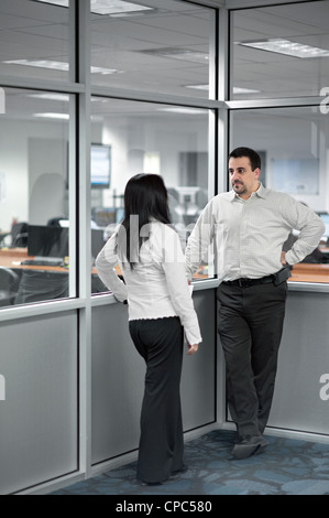 Two people talking in a corner in an office. Stock Photo