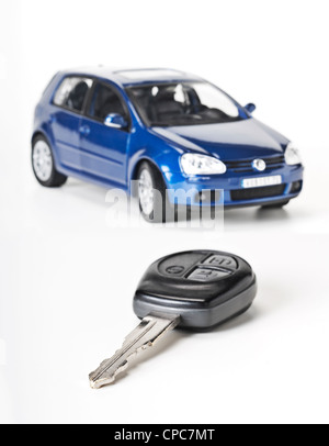 Car key as a close-up and a blue car in the background. Stock Photo