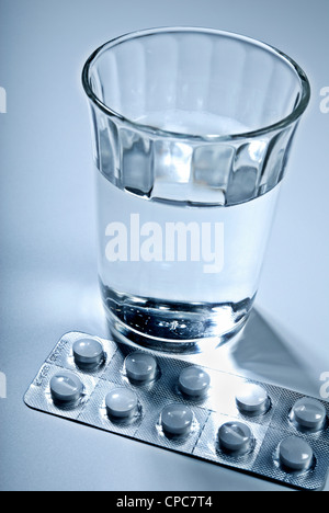Tablets in a blister pack and a glass of water. Stock Photo
