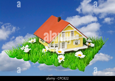 Model house on artificial grass against a blue sky as a symbol of a dream house. Stock Photo