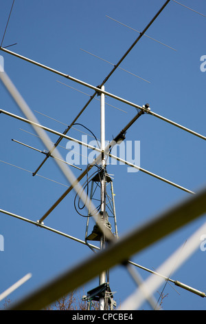 Three element HF radio transmitting mast with Yagi and HF Antenna set on a tower mast against a blue sky Stock Photo