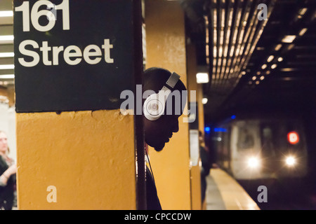A music listener wears his over the ear Beats by Dr. Dre brand headphones on a subway platform Stock Photo