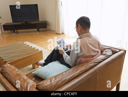 Senior man using tablet PC on a sofa Stock Photo
