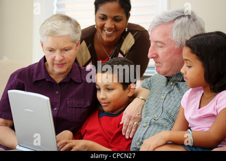 Grandparents together with their family at home using computer Stock Photo