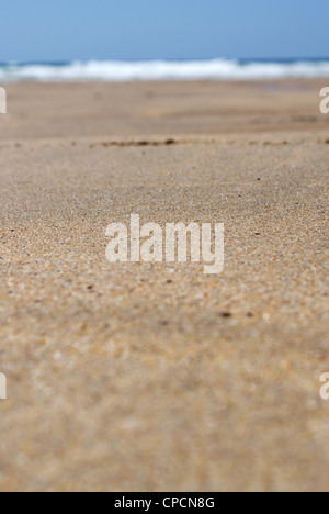 Focus and close up on a sandy pebble beach. A sun bed with a woman in