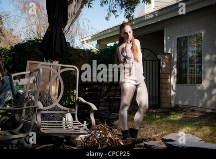 Woman standing in dilapidated backyard Stock Photo