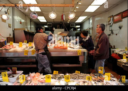Fishmonger selling fish to a customer in on Mott Street, Chinatown New York Stock Photo