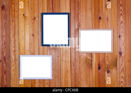 On the old yellow rural home wall of pine wood planks hung empty white pictures frames Stock Photo