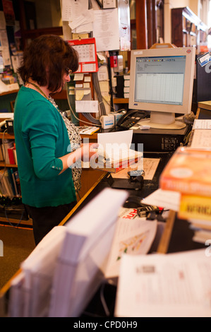A woman librarian issuing books in the old Aberystwyth Carnegie funded public lending library, Wales UK Stock Photo