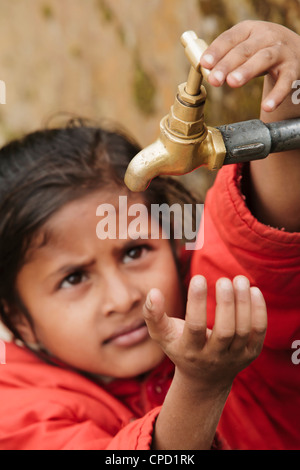 Young girl checking to see if the communal village water tap has water, as it runs dry daily, Pokhara, Nepal, Asia Stock Photo