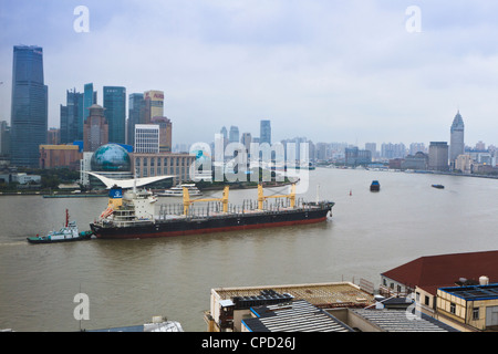 Large transport ship and tug on the Huangpu River that runs through Shanghai, China, Asia Stock Photo