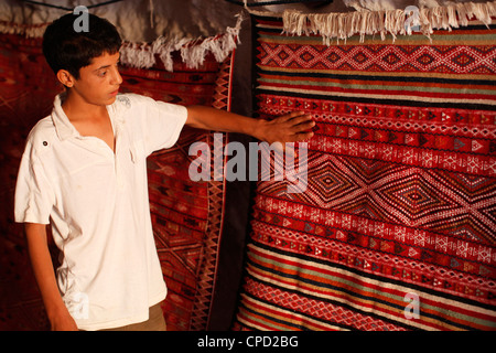 Boy showing a rug in a carpet shop, Toujane, Tunisia, North Africa, Africa Stock Photo