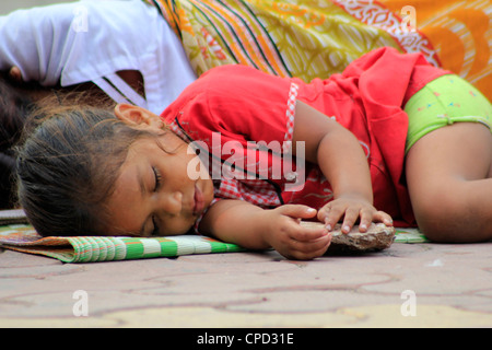 A homeless street kid sleeping on the roadside in Mumbai, India Stock Photo