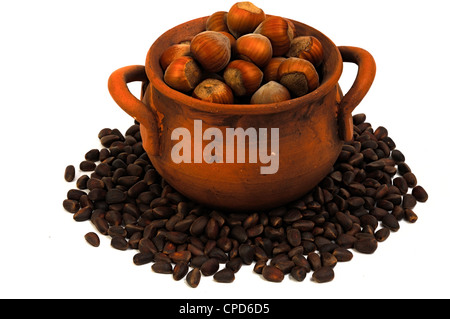 pot with hazelnuts, pine nuts surrounded, isolated, close-up Stock Photo