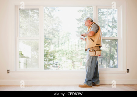 Caucasian carpenter using digital tablet in empty room Stock Photo